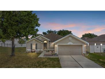 Charming single-story home with a well-manicured lawn and a two-car garage at dusk at 323 Azincourt Ln, Kissimmee, FL 34759