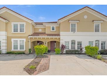 Inviting townhome showcasing a Mediterranean-style facade and well-manicured landscaping under a clear blue sky at 4751 Terrasonesta Dr, Davenport, FL 33837