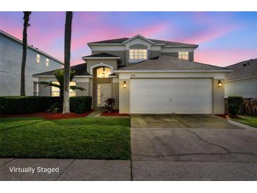 Charming two-story home featuring a manicured lawn, a two-car garage, and a beautifully lit entrance at 1048 Lake Berkley Dr, Kissimmee, FL 34746