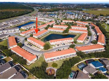 A beautiful aerial view of townhomes surrounding a pond in a well-maintained community with mature trees and landscaping at 1149 S Beach Cir, Kissimmee, FL 34746