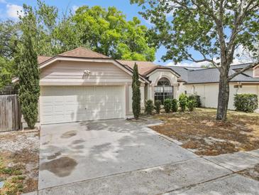 Charming single-story home featuring a two-car garage, arched window, and manicured landscaping at 1345 Tindaro Dr, Apopka, FL 32703