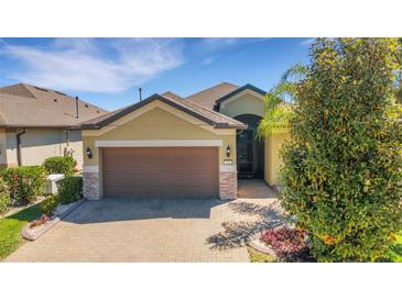 Charming home featuring a brown garage door, stone accents, and a beautiful brick driveway at 164 Montoro Ln, Davenport, FL 33837