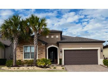 Charming single-story home featuring a stone facade, lush landscaping, and a two-car garage at 333 Almansa St, Davenport, FL 33837