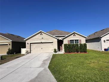 Charming single-story home with a well-maintained lawn and a two-car garage under a clear blue sky at 377 Holly Berry Dr, Davenport, FL 33897
