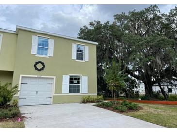 Two-story home with attached garage, white trim, manicured landscaping, and stunning mature tree at 4247 Shackelford Ct, Orlando, FL 32824