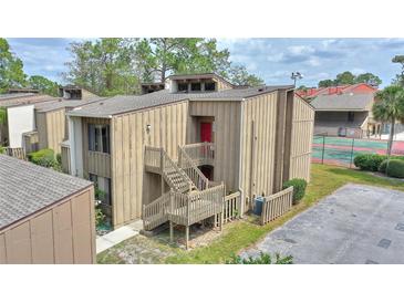 Inviting multi-level townhome featuring exterior staircase with red door and views of the community's tennis courts at 5316 Burning Tree Dr # A09-2, Orlando, FL 32811