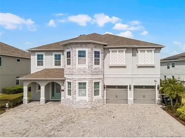Stunning two-story home with a three-car garage and a beautifully paved driveway and a stone facade at 7665 Fairfax Dr, Kissimmee, FL 34747