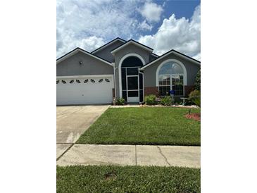 Charming single Gathering home with a well-manicured lawn and attached two-car garage at 8074 Santee Dr, Kissimmee, FL 34747