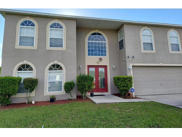 Two story home with large windows and a red double door at 907 Gloucester Ct, Kissimmee, FL 34758