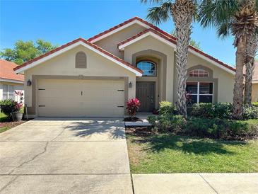 Charming single-story home with a terra cotta roof, palm trees, manicured lawn and attached two car garage at 1102 Solana Cir, Davenport, FL 33897
