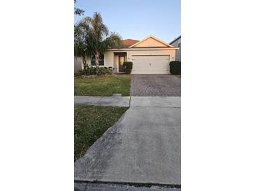 Charming single-story home with manicured lawn, mature trees, and a brick-paved driveway at 5340 Jubiloso Dr, St Cloud, FL 34771