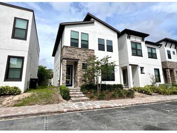 Contemporary two-story home featuring a stone facade, manicured landscaping, and a brick walkway at 236 Villa Domani Cir, Davenport, FL 33896