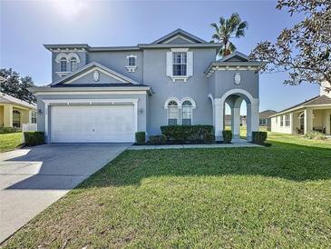Charming two-story home with manicured lawn and attached two car garage, and ornate architectural details at 205 Minniehaha Cir, Haines City, FL 33844