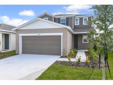 Charming two-story home featuring a gray-brown exterior, a two-car garage, and fresh landscaping at 6381 Clover St, Lake Hamilton, FL 33851