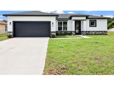 Charming single-story home boasts a modern design with a gray garage door and well-manicured lawn at 308 Miami Ln, Kissimmee, FL 34759
