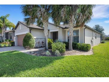 Charming single-story home with well-manicured lawn, stone accents, and beautiful palm trees at 1005 Salamanca Pl, Davenport, FL 33837