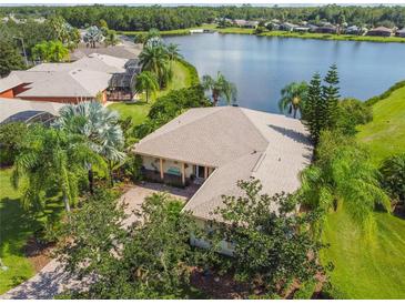 Aerial view of a landscaped home near a lake, featuring mature trees and meticulous landscaping at 107 Belzano Pl, Poinciana, FL 34759