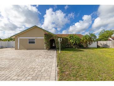 Charming single-story home with lush landscaping, arched entryway, and a brick driveway at 11242 Stone Gate Ct, Orlando, FL 32837