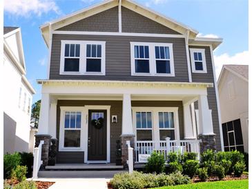Charming two-story home featuring a welcoming front porch with stylish columns and beautifully landscaped yard at 2057 Celebration Blvd, Celebration, FL 34747