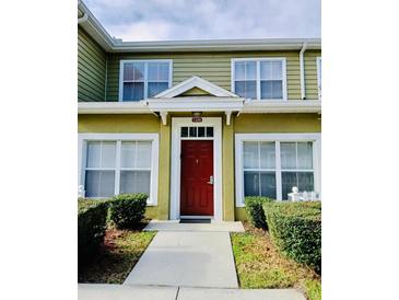 Inviting townhouse with a vibrant red front door and well-manicured landscaping at 2610 Lodi Cir # 104, Kissimmee, FL 34746