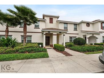 Inviting townhome exterior featuring lush landscaping and a covered entrance at 9075 Dogleg Dr, Davenport, FL 33896