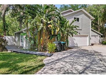Charming home featuring two garages, lush tropical landscaping, and a welcoming gray wood finish at 13959 Marine Dr, Orlando, FL 32832