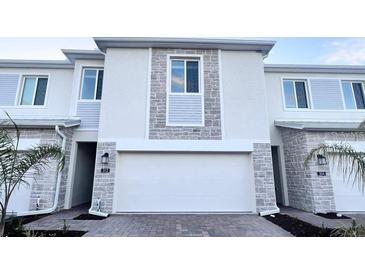 Attractive townhome featuring a two car garage, stone facade, and well manicured landscaping at 312 Nine Iron Dr, Davenport, FL 33896