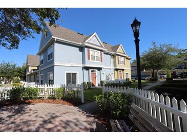 Charming two-story townhome with a light blue facade, white picket fence, and well-manicured lawn at 4004 Santa Maria Dr # 108, Kissimmee, FL 34741