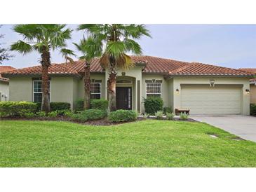 Inviting single-story home with mature landscaping, manicured lawn, and a terracotta tiled roof at 4072 Oaktree Dr, Davenport, FL 33837