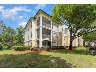 Inviting condo exterior with screened balconies, mature trees, and lush landscaping on a partly cloudy day at 8923 Legacy Ct # 19-102, Kissimmee, FL 34747