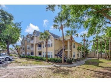 Well-maintained building featuring a yellow exterior and lush landscaping, including palm trees at 1051 S Hiawassee Rd # 2127, Orlando, FL 32835