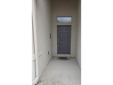 Covered entryway features a gray front door with a transom window and a small porch area at 130 Highland Meadows St, Davenport, FL 33837