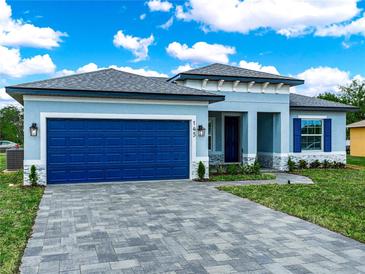 Charming single-Gathering home featuring blue exterior, a blue garage door, and manicured landscaping at 145 Willow Dr, Poinciana, FL 34759