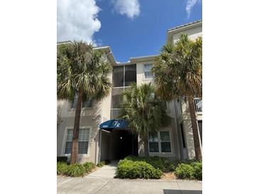 Three-story condo building with palm trees and covered entrances under a blue awning at 3321 Whitestone Cir # 204, Kissimmee, FL 34741