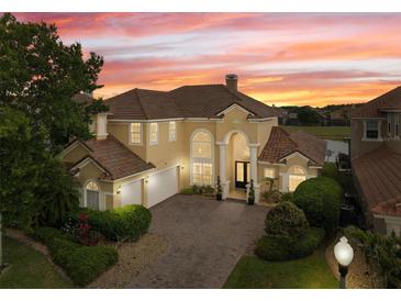 Stunning home showcases tile roof, lush landscaping, brick driveway, and ample curb appeal with a picturesque sunset backdrop at 2234 Callaway Ct, Davenport, FL 33837