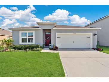 Charming single-story home featuring a two-car garage, well-manicured lawn, and inviting front entrance at 2874 Turnstone Run, Harmony, FL 34773