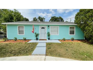 Charming single-story home featuring a vibrant turquoise exterior and well-maintained front yard at 4765 Lake Shore Dr, St Cloud, FL 34772