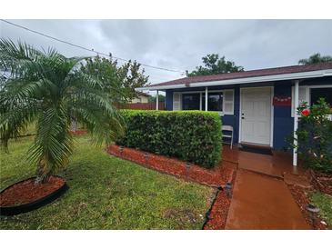 Charming single-story home boasts a well-manicured front yard with lush green landscaping, shrubs and palm tree at 1617 Emmett St, Kissimmee, FL 34741