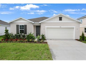 Charming single-story home boasts a manicured lawn and an attached two-car garage at 1126 Olivine Ave, Dundee, FL 33838