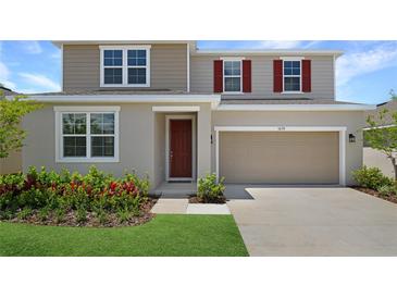 Charming two-story home featuring red shutters, neutral siding, manicured lawn, and a two-car garage at 1650 Sugarbelle Cir, Mascotte, FL 34753