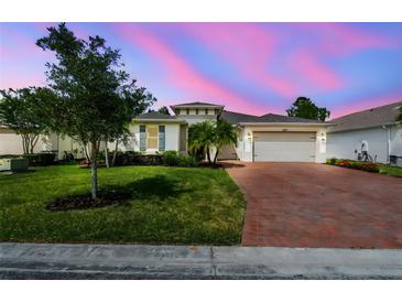 Charming single-story home with lush lawn, mature trees, and a brick driveway under a colorful, twilight sky at 789 Cielo Trl, Kissimmee, FL 34759