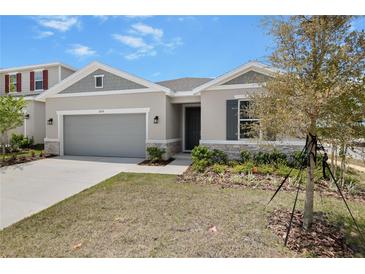 Charming single-story home with a two-car garage, stone accents, and well-maintained landscaping at 1654 Sugarbelle Cir, Mascotte, FL 34753