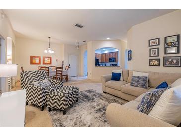 Inviting living room featuring modern furniture, neutral tones, and a view into the adjacent dining area and kitchen at 3301 Whitestone Cir # 203, Kissimmee, FL 34741