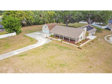 Charming home with a long driveway, detached garage, covered porch, and ample front yard space at 7938 Riffle Ln, Orlando, FL 32818