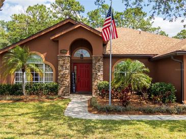 Charming home featuring a red front door, stone accents, well-kept lawn, and American flag at 20249 Macon Pkwy, Orlando, FL 32833