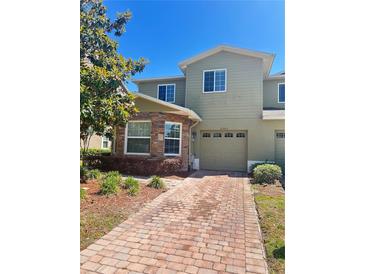 Inviting two-story townhome featuring stone accents, a one-car garage, and a brick-paved driveway at 2305 Chatham Place Dr, Orlando, FL 32824