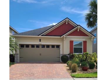 Charming single Gathering home featuring a brick paved driveway, 2 car garage, and red accents on the roof and window shutters at 2522 Nouveau Way, Kissimmee, FL 34741