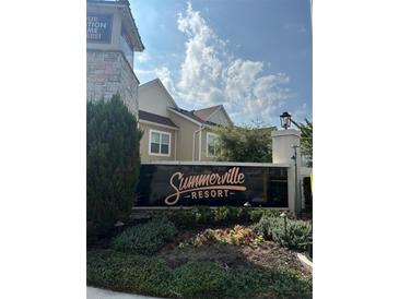 The Summerville Resort community sign is surrounded by flowering bushes and mature trees at 7544 Sunville Ave # 7544, Kissimmee, FL 34747