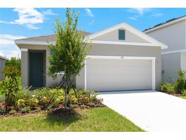 Charming single-story home with a two-car garage, beautifully landscaped front yard, and neutral-toned exterior at 828 Lake Dell Rd, Dundee, FL 33838
