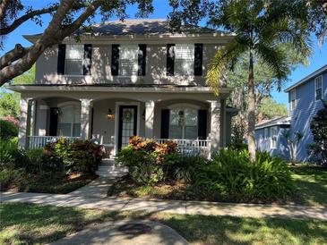 Charming two-story home featuring lush landscaping, a covered porch and large windows at 9803 Sweetleaf St, Orlando, FL 32827